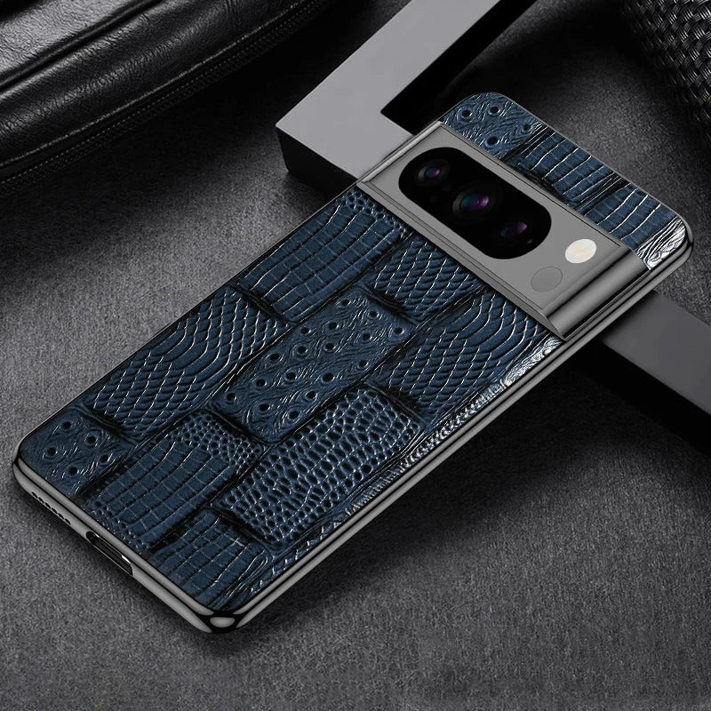 A smartphone with a textured blue crocodile-patterned case is placed on a gray surface, showcasing its sleek design and camera module.