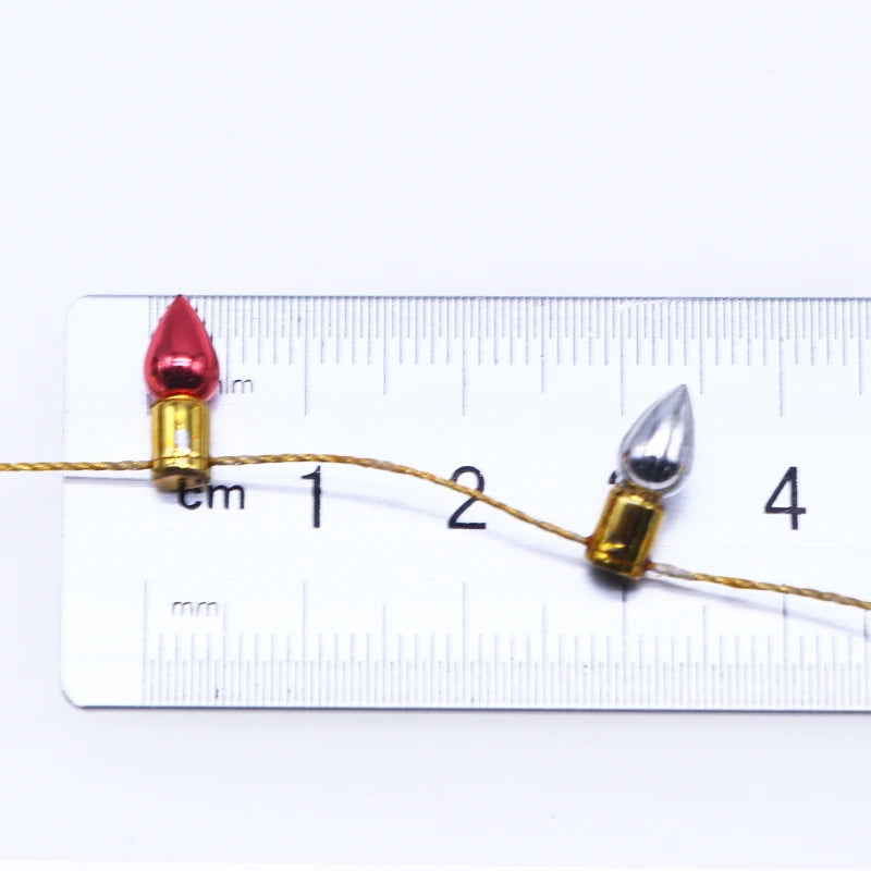 Miniature red and silver LED bulbs on a thin wire are placed next to a ruler, showcasing their small size at about 1.5 cm each.