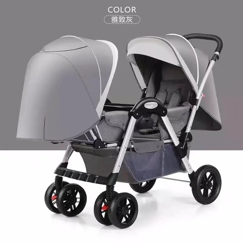 Gray double stroller with two seats, adjustable canopies, and a sleek silver frame. Features six wheels, a comfortable handle, and under-seat storage in a studio setting.
