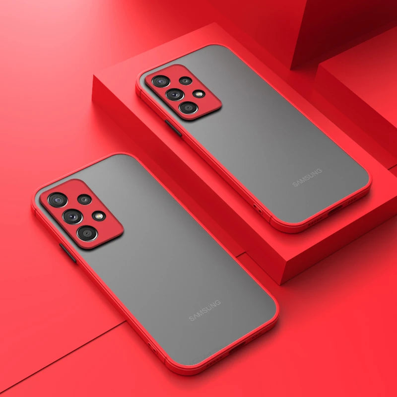 Two Samsung smartphones with gray backs and red cases are displayed on a vibrant red surface. Each phone has a quad-camera setup with a red camera module.