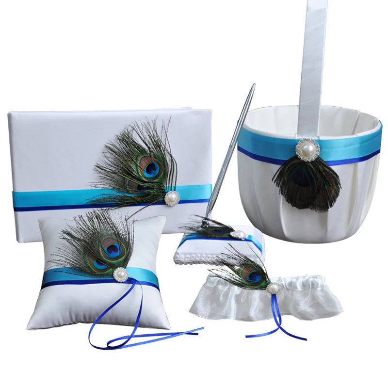 White bridal accessories set featuring peacock feathers and blue ribbons, including a basket, guest book, pen, ring pillow, garter, and envelope.