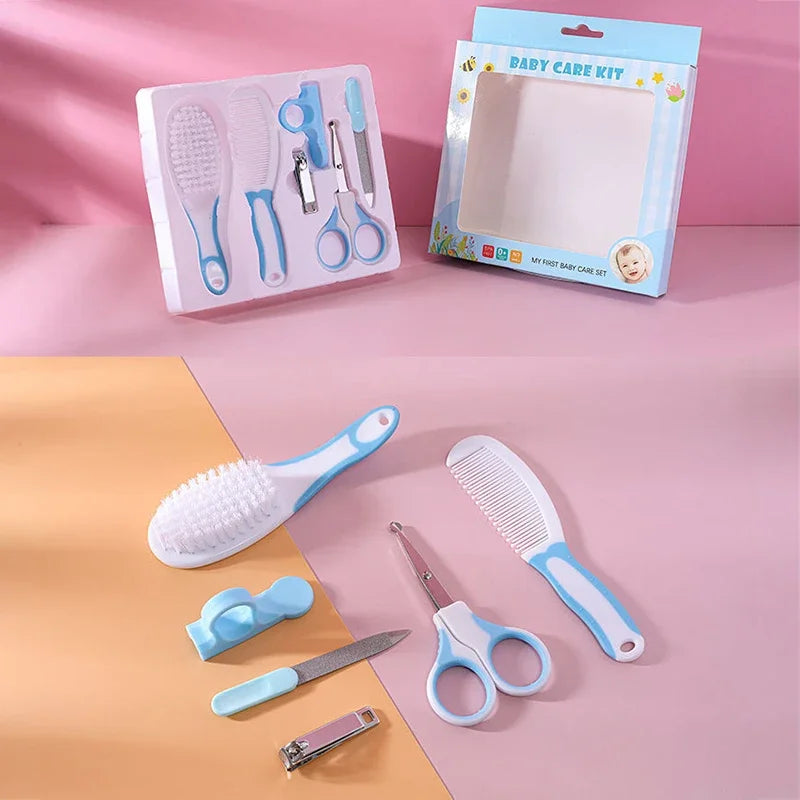 Baby care kit with brush, comb, scissors, nail clippers, and file in pastel colors. The set is displayed on a pink surface with an open packaging box nearby.