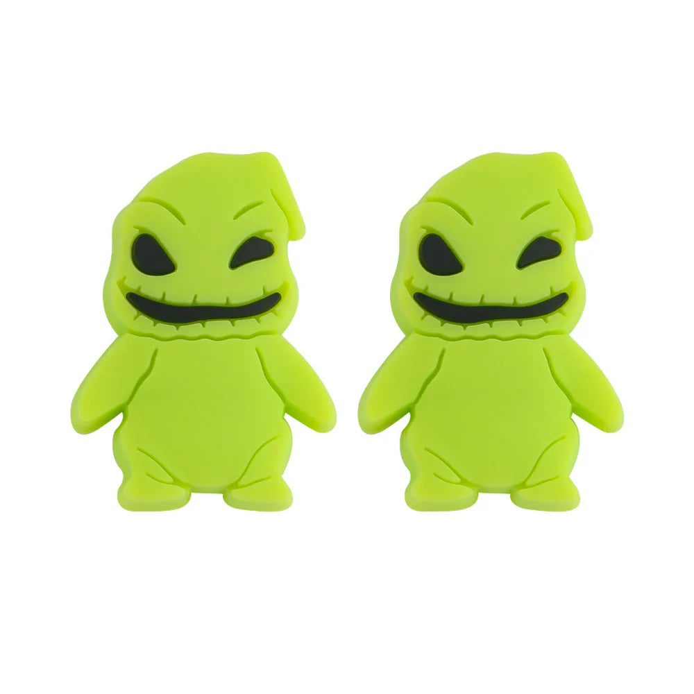 Two vibrant green figurines with stitched smiles and dark eyes, resembling playful, rounded ghost-like characters against a white background.