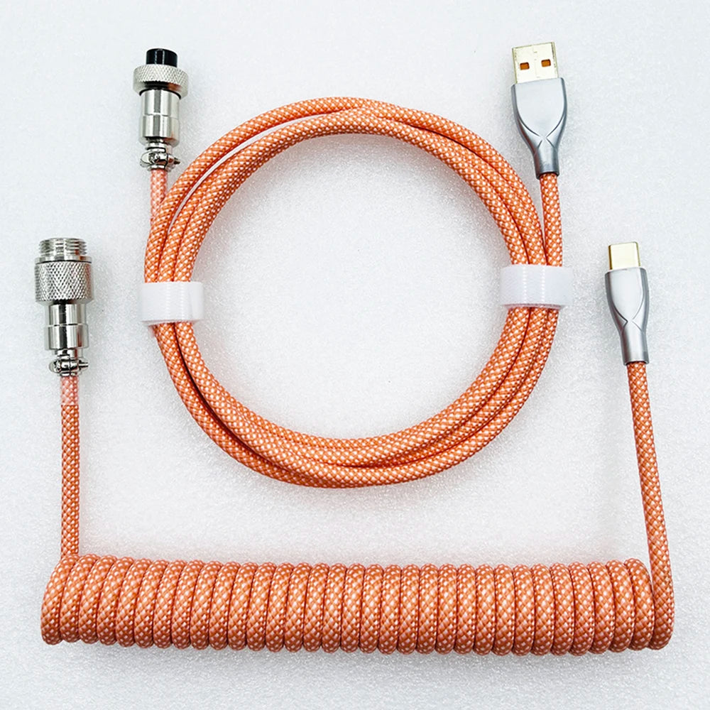 Orange braided USB cable with coiled section, featuring a gray USB-A connector and a gray USB-C connector. Includes durable metal connectors for secure connections.