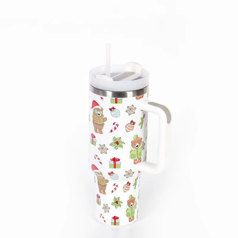 Holiday-themed travel mug with a handle, featuring cartoon bears in winter attire, candy canes, gifts, and holly on a white background. Equipped with a lid and straw.