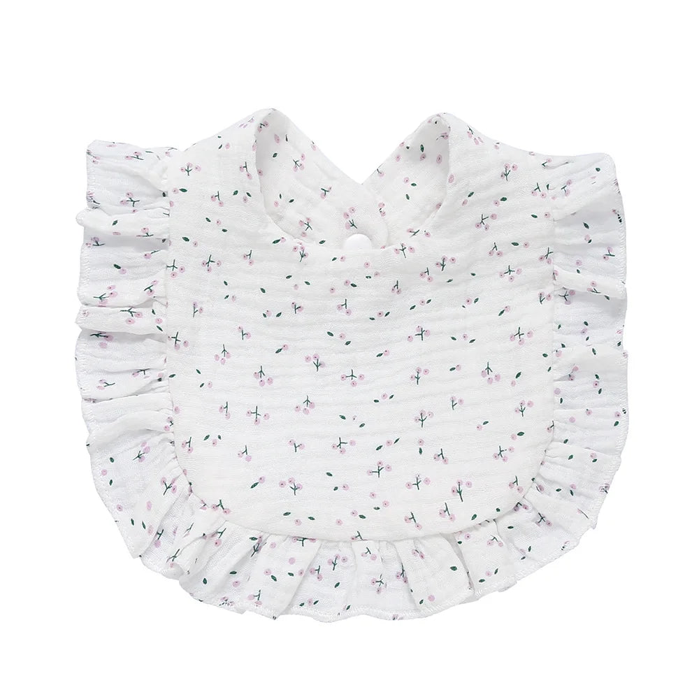 White baby bib with small pink and green floral pattern, featuring ruffled edges and a round neckline.