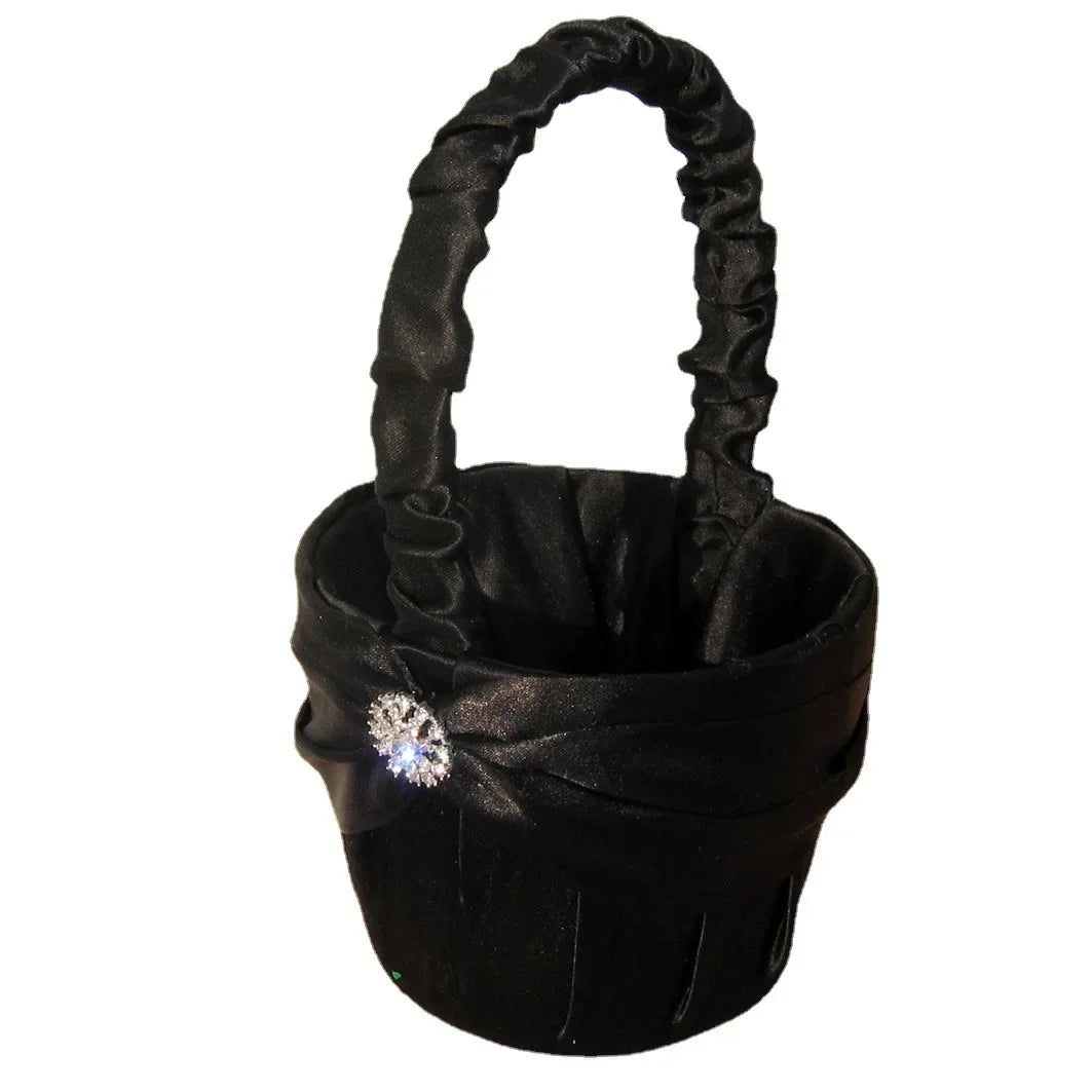 Elegant black fabric basket with a ruffled handle and adorned with a sparkling rhinestone brooch on the side. Ideal for decorative purposes or special occasions.