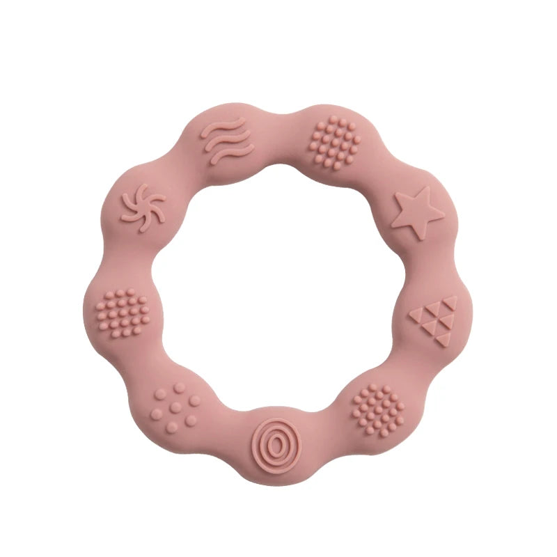 Pink silicone teething ring with wavy edges and various embossed textures, including stars, spirals, dots, and waves, designed for sensory stimulation.