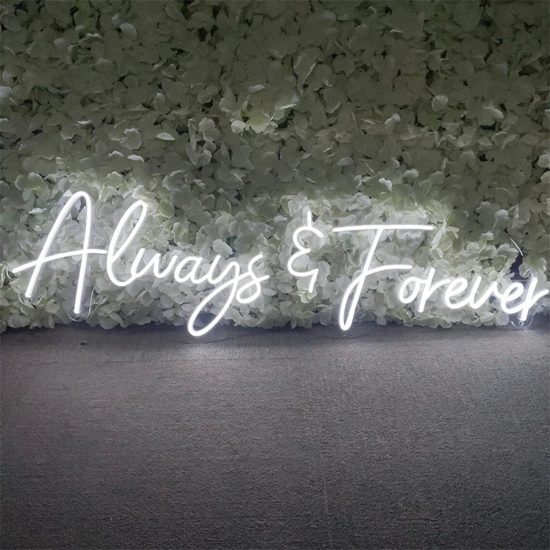 Neon sign reading "Always & Forever" in elegant script, set against a backdrop of white hydrangea flowers.