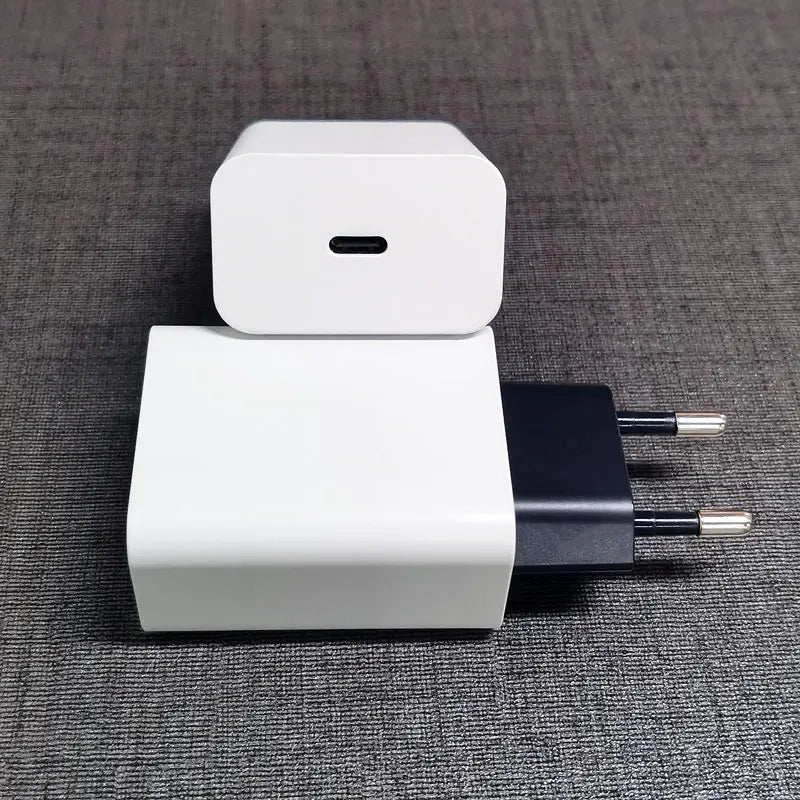 Two white USB wall chargers with European plugs on a gray surface. One charger has a USB-C port, facing upwards, and the other shows its prongs, positioned horizontally.