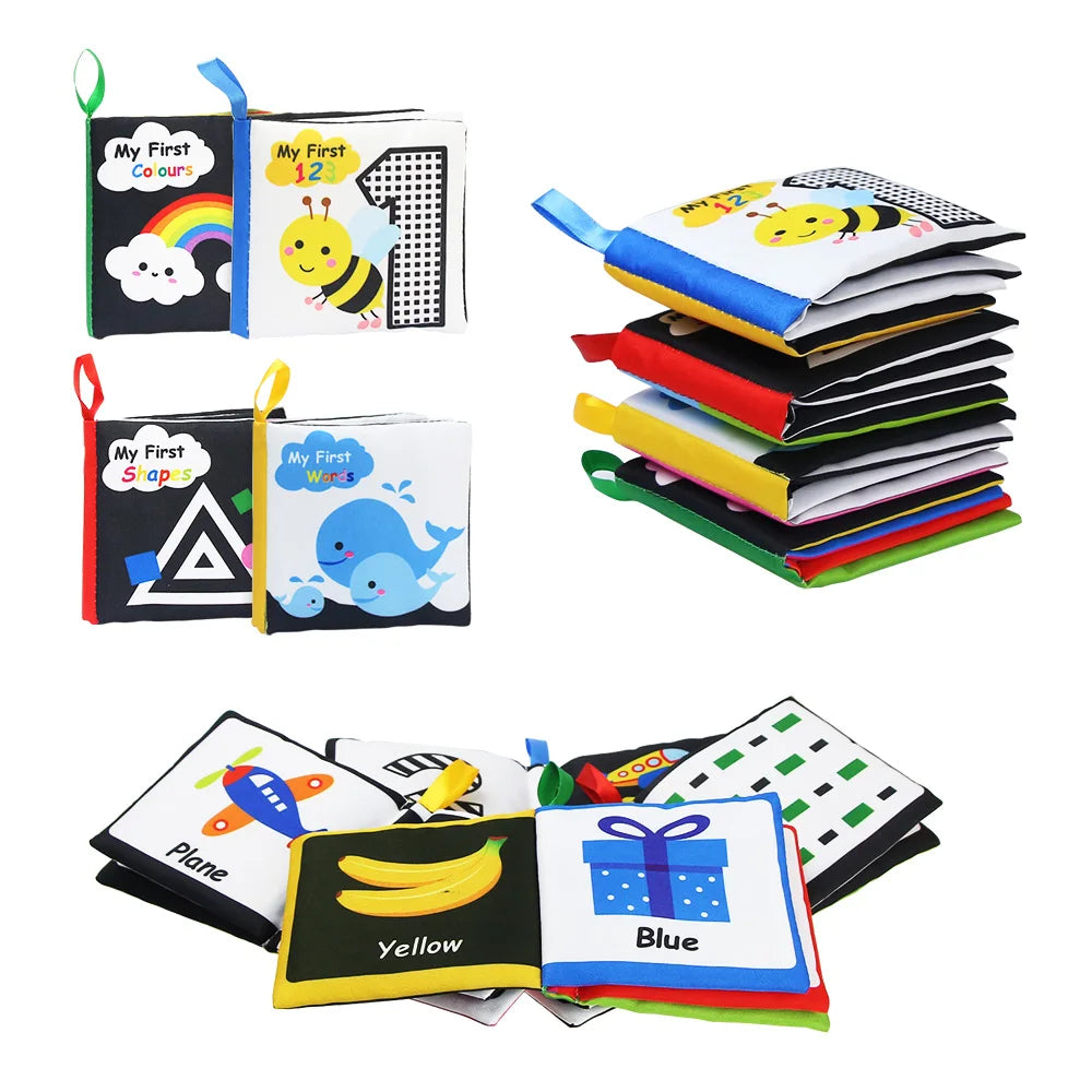 Soft baby books featuring colorful designs, including rainbows, bees, shapes, and animals. Titles include "My First Colours" and "My First Words." The books are stacked and opened.