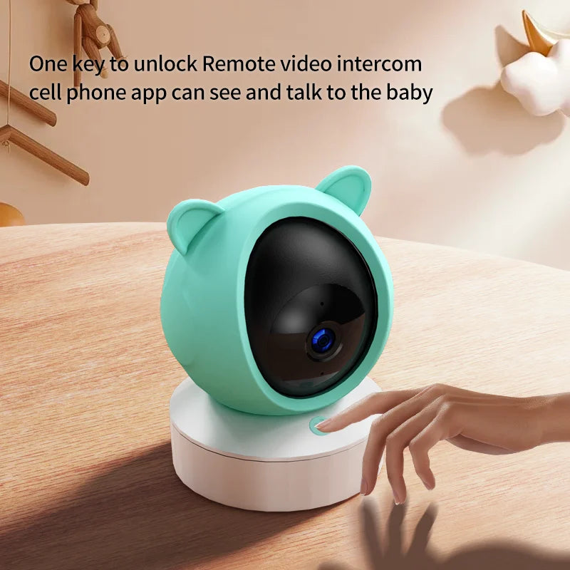 A cute, bear-shaped baby monitor camera with a turquoise casing on a wooden surface. A hand is reaching towards the device, with text about remote video intercom capabilities above.