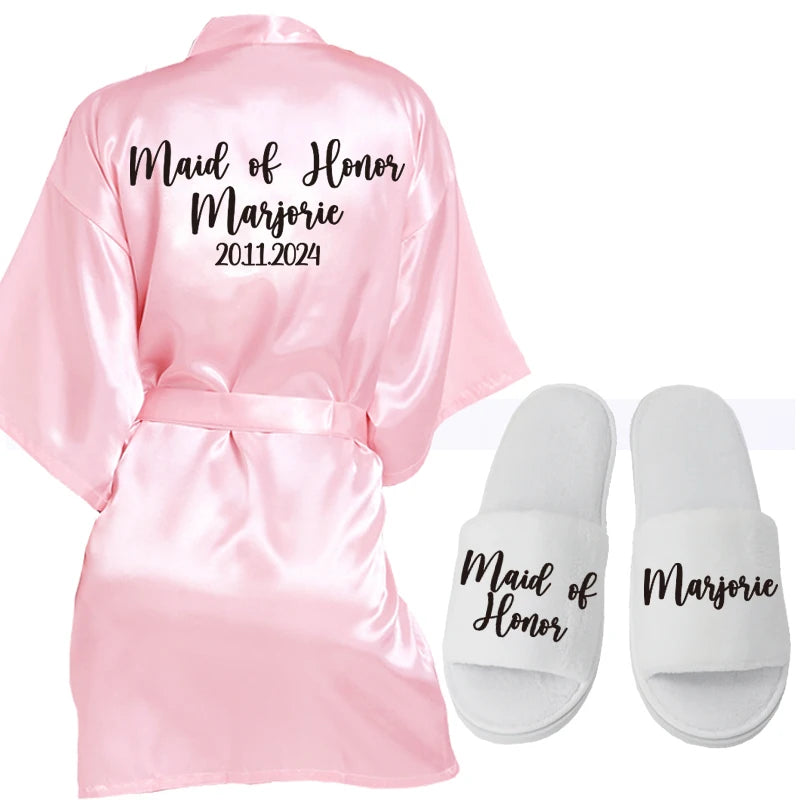 Pink satin robe and white slippers set. Robe text: "Maid of Honor Marjorie 2011-2024." Slippers text: "Maid of Honor" on left, "Marjorie" on right.