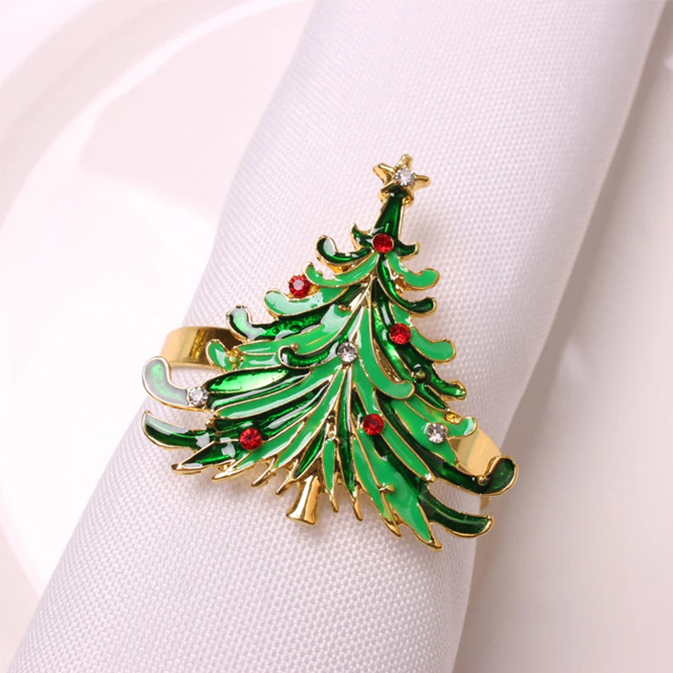 Festive napkin ring shaped like a Christmas tree with green leaves, gold accents, and red ornaments, wrapped around a white napkin on a plate.