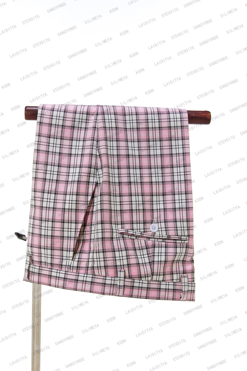Pink and black plaid pants neatly folded over a wooden rod, featuring a front button and pocket, displayed against a white background.