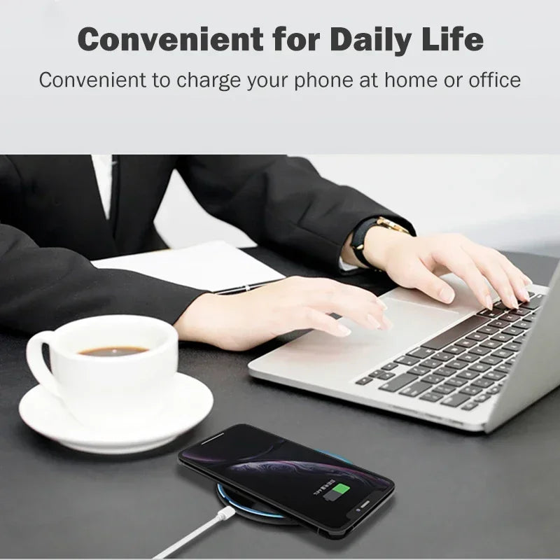 Person in business attire types on a laptop beside a cup of coffee. A smartphone charges on a wireless pad, illustrating convenience for daily life at home or office.
