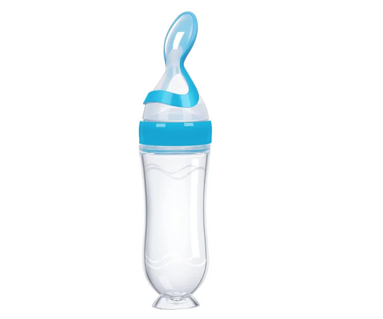 Transparent feeding bottle with blue accents and a spoon-shaped dispenser. The bottle has a wide neck and ergonomic design, standing upright on a flat base.