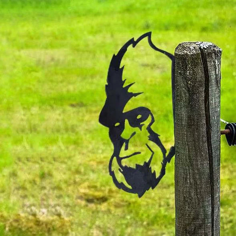 Metal silhouette of Bigfoot's face attached to a wooden post, set against a grassy background.
