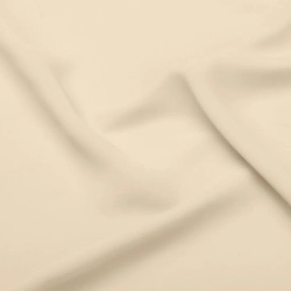 Close-up of a soft, beige fabric with gentle folds and a smooth texture, creating subtle shadows and highlights on the material's surface.