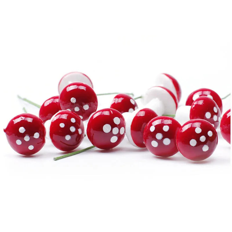 Red and white artificial mushrooms with polka dots, resembling toadstools, scattered on a white background. They have thin green stems for decoration or craft use.