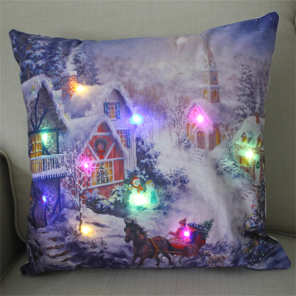 Festive pillow with a snowy village scene, featuring illuminated houses, a horse-drawn sleigh, snowmen, and colorful lights on a wintry backdrop.