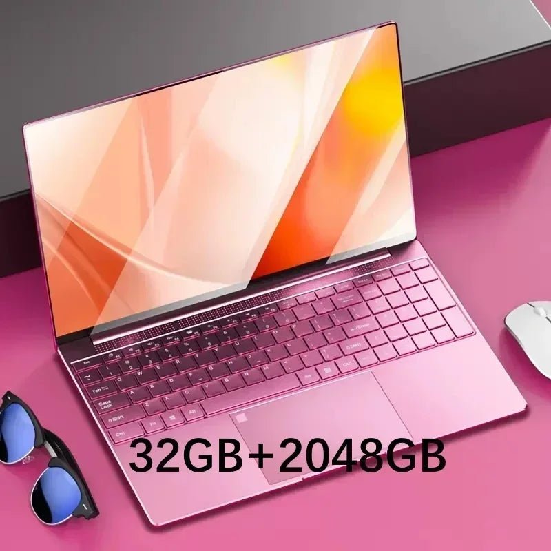 Pink laptop on a pink surface, displaying orange abstract wallpaper. Text overlay shows "32GB+2048GB." Nearby are sunglasses and a gray mouse.