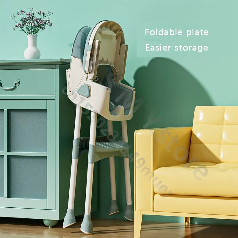 A foldable high chair with a green and white design is propped against a light green wall. It's beside a green cabinet with a vase and a yellow sofa, emphasizing easy storage.