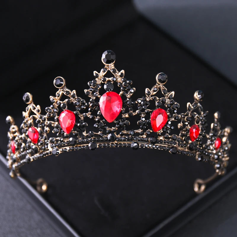 An ornate crown adorned with black and red gemstones set in a gold framework, featuring prominent red teardrop-shaped gems, displayed on a black surface.