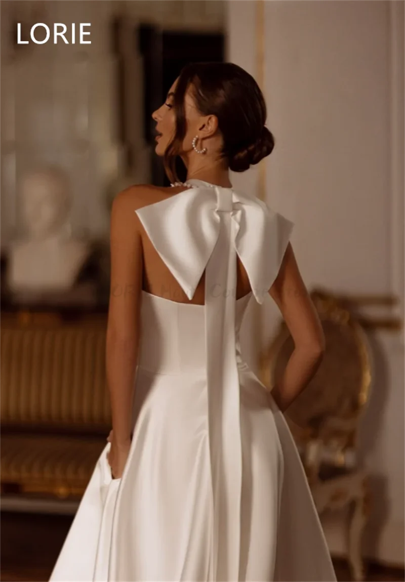 Rear view of a woman in an elegant white gown with a large bow at the back, set in a refined, classic interior featuring elegant furniture and muted decor.