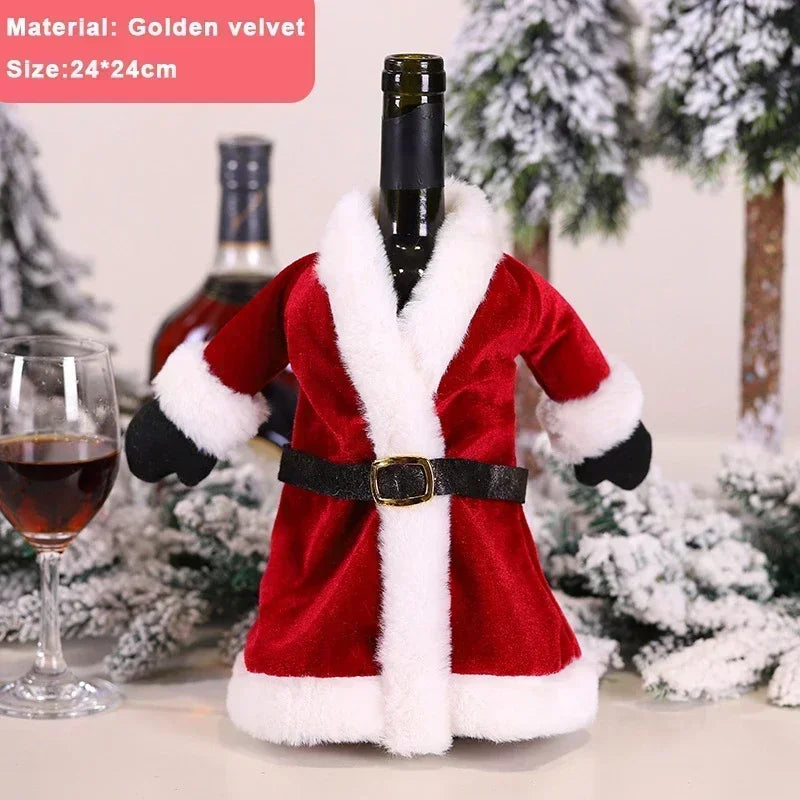 Bottle dressed in a Santa suit made of golden velvet, with a black belt and white trim. It's on a snowy surface with trees in the background and a glass of red wine.