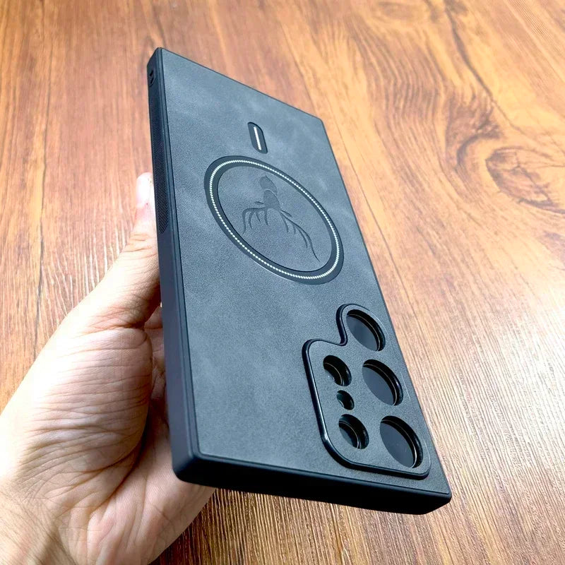 A hand holds a black, textured smartphone case with a spider emblem and multiple camera cutouts on a wooden surface.