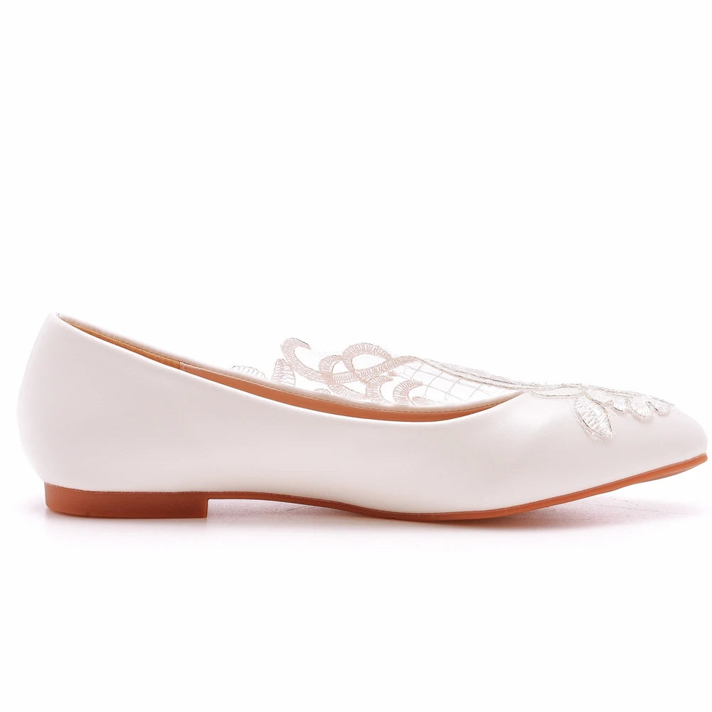 White ballet flat with intricate lace detailing on the upper, featuring a low heel and a smooth finish. The shoe has a sleek design ideal for a formal or wedding occasion.