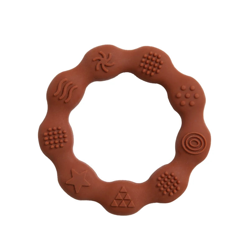 Brown silicone teething ring with a wavy shape. Features various embossed textures including a spiral, circles, star, triangle, and wave patterns around the edge.