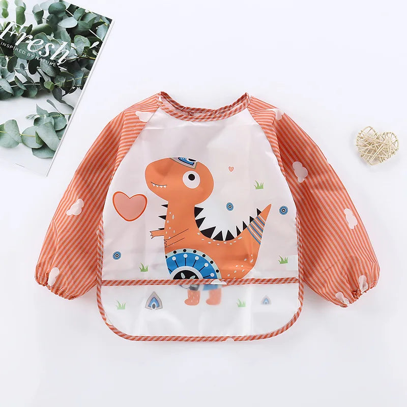 Children's orange and white long-sleeved bib with a cute dinosaur illustration, surrounded by hearts. The sleeves have striped patterns and white cloud designs.