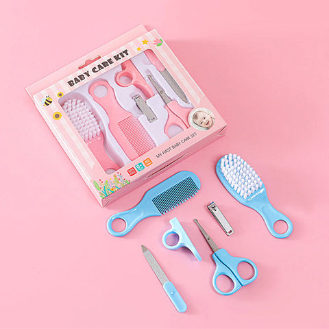 Baby care kit on a pink background, includes a blue and pink comb, brush, scissors, nail clippers, and filer. Packaged set labeled "Baby Care Kit" with floral decoration.
