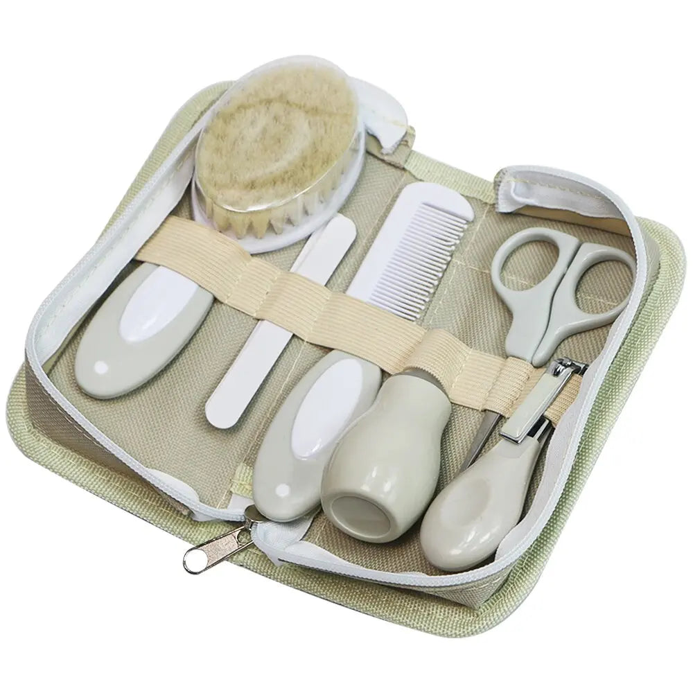 Baby grooming kit in an open zippered case, including a soft brush, comb, scissors, nail clippers, and files. The items are secured with elastic bands in a khaki bag.