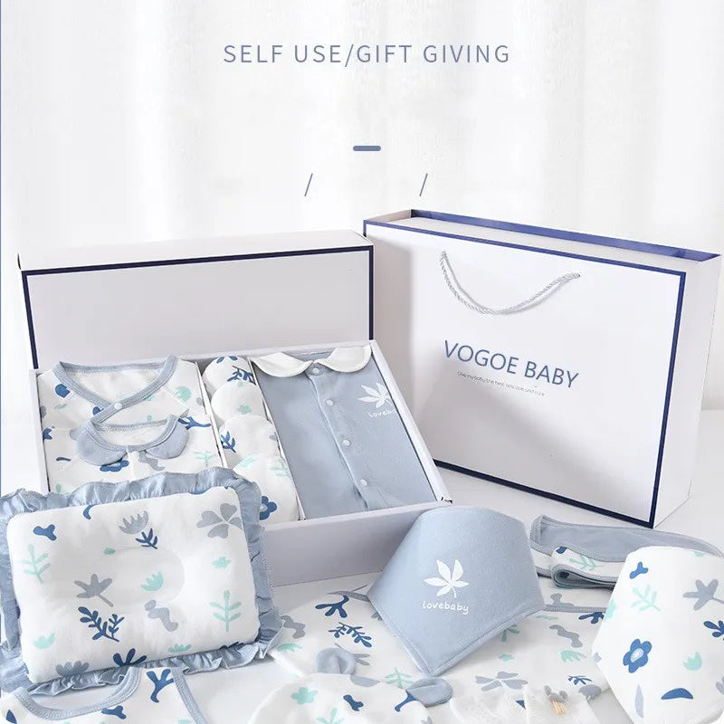 Gift set with pastel baby clothes and accessories in a white box. Includes a blue shirt, patterned onesies, and cloths. Label reads "Vogoe Baby". Shopping bag included.