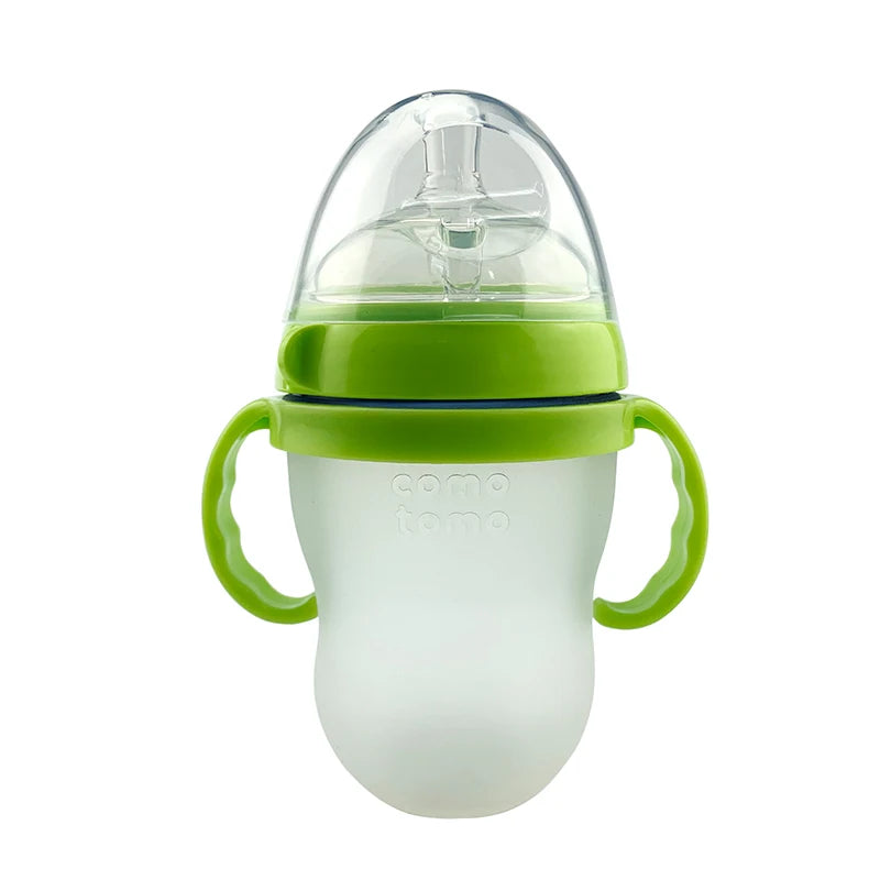A clear sippy cup with green handles and lid, featuring a soft spout and transparent cover. Designed for toddlers, it combines functionality with an easy-grip design.