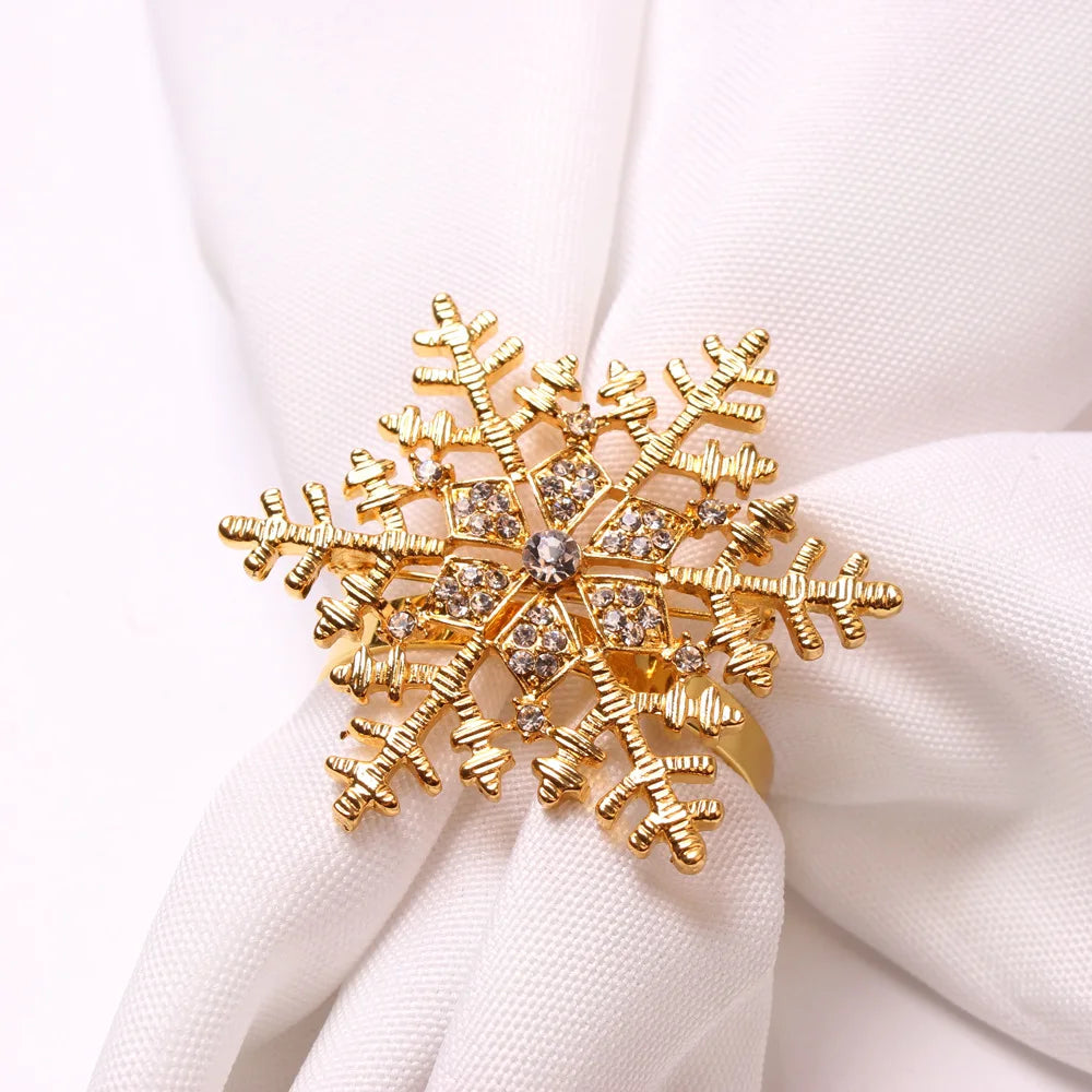 Golden snowflake-shaped ring adorned with sparkling crystals, elegantly placed on white fabric for a sophisticated display.
