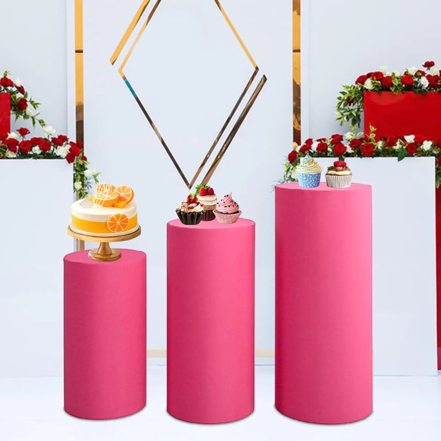 Three pink pedestals display desserts: a citrus cake on the left, chocolate and berry cupcakes in the middle, and assorted cupcakes on the right. Background has red floral decor.