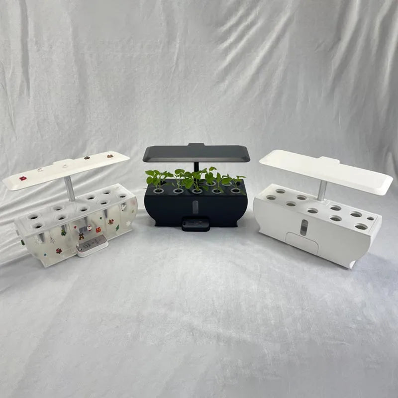 Three hydroponic indoor garden kits on a white surface, featuring white, black, and white containers. The black one has young plants growing, while the others are empty.
