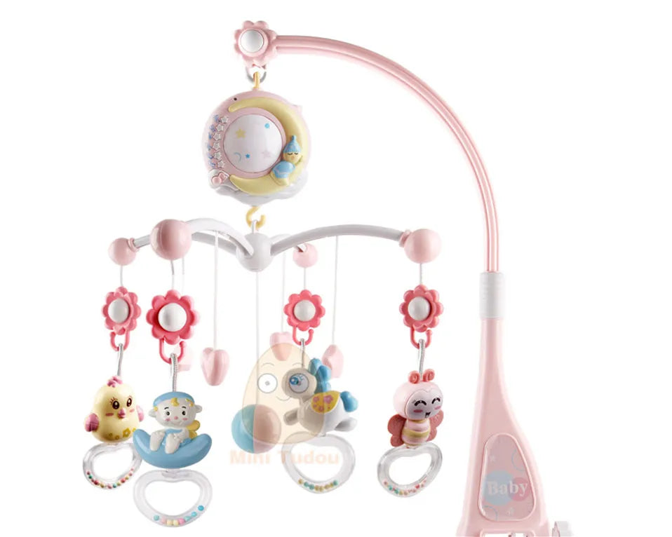A pink and white crib mobile features colorful hanging toys including flowers and animal figures. The mobile is adorned with a crescent moon and stars at the top.