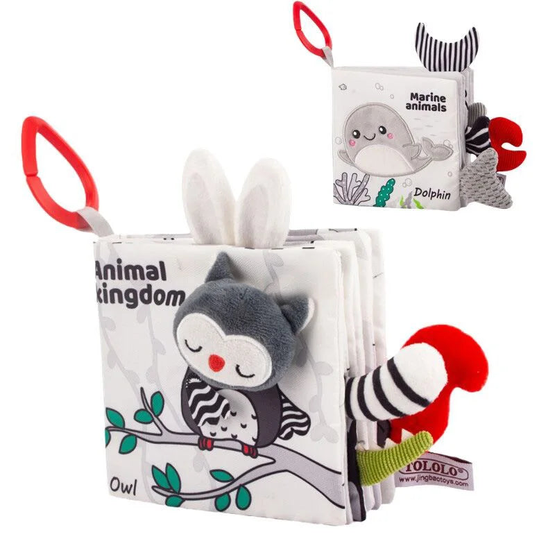 Soft baby books with plush animal designs. One book features an owl with a branch, labeled "Animal Kingdom," and the other features a dolphin, labeled "Marine Animals," both with red handles.