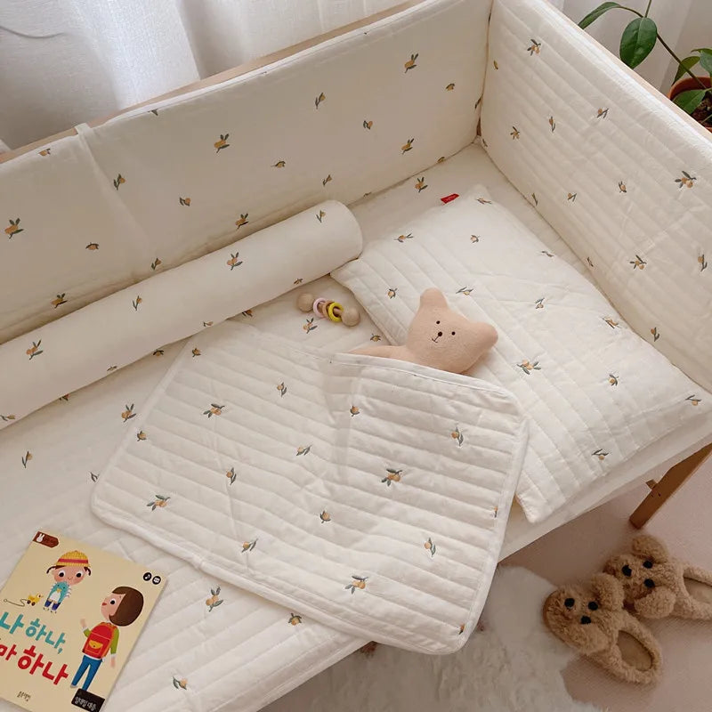 Cozy nursery with floral-patterned bedding, a plush bear, a baby pacifier, a children's book, and fluffy bear slippers on the floor. A leafy plant is in the corner.