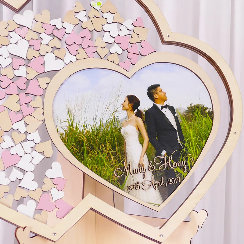Heart-shaped wedding photo frame with wooden pink and white hearts surrounds a couple in wedding attire. Text: "Mady & Henry, 30th April, 2019."