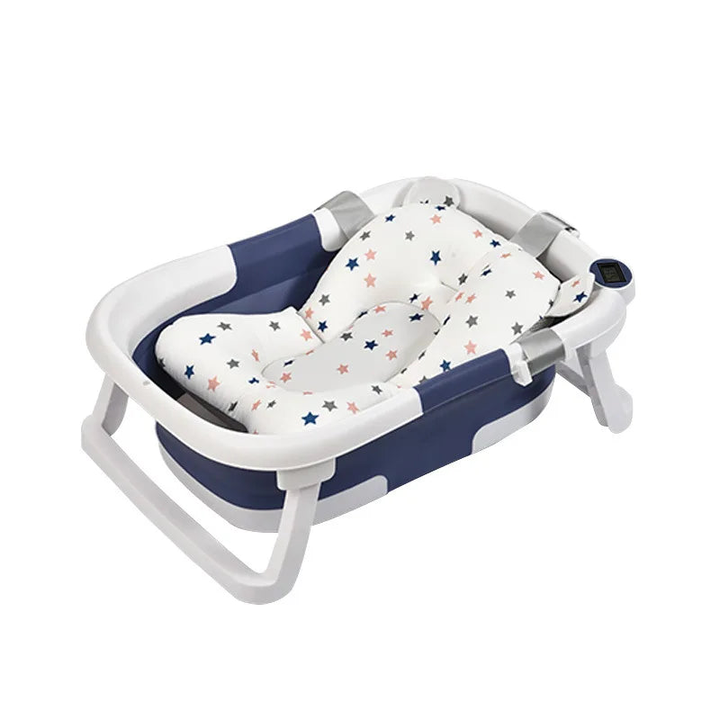 A foldable baby bathtub with a white cushion featuring multicolored stars. It has a blue and white frame with sturdy legs and a digital thermometer on the side.