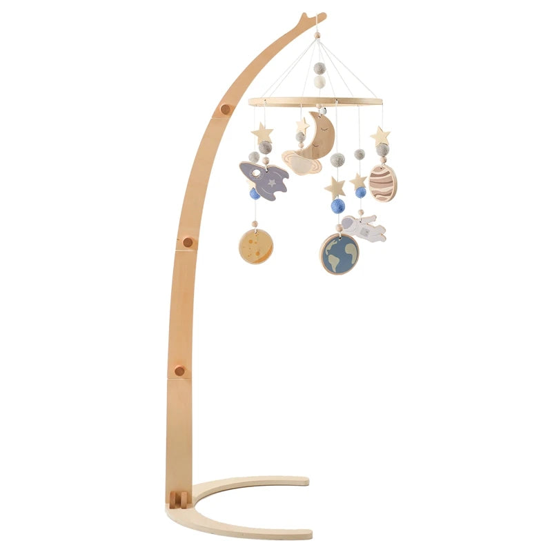 A wooden baby mobile featuring planets, stars, a moon, a rocket, and an astronaut, all suspended from a curved wooden arm, designed to hang over a crib.