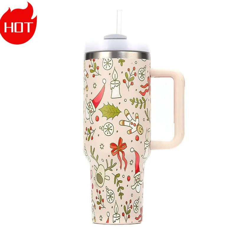 Tall travel mug with a festive design featuring reindeer, Santa, snowflakes, and holly. It has a handle and a lid with a straw. A red "HOT" symbol is in the top left corner.