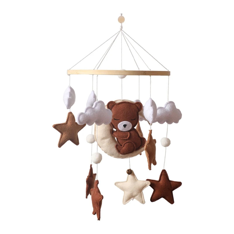 A baby mobile featuring a plush brown bear sleeping on a moon, surrounded by white clouds and various shades of brown and cream stars, all hanging from a wooden ring.