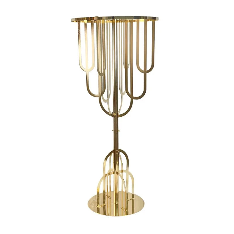 Elegant gold metal table with a round top and intricate U-shaped leg design. The reflective base and symmetrical pattern enhance its luxurious appearance.